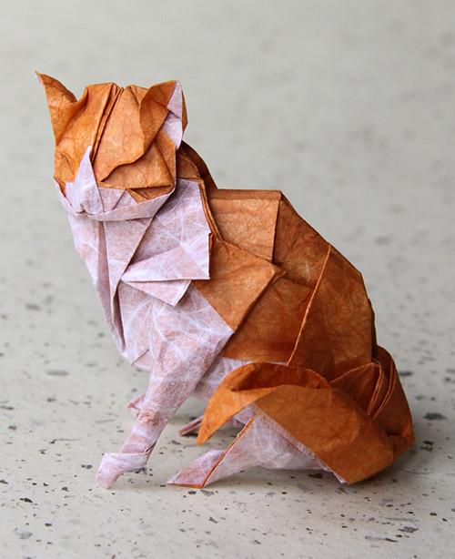 Photography. A color photo of a folded origami cat based on motifs by Katsuta Kyohei. An orange cat with a pink belly and legs, folded from transparent patterned tissue paper, stands on a gray background. A wonderful example of this Asian folding art.
Info: Folded from Lim Liang paper with Unryu paper. Size: 28 x 28 cm.
"Nyanko Sensei" shows more beautiful examples on his Flickr account.